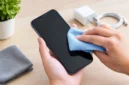 Membersihkan layar HP menggunakan kain mikrofiber secara perlahan dapat membantu mengangkat debu dan sidik jari tanpa memberikan tekanan berlebihan (Ilustrasi AI: sisipublik.com)