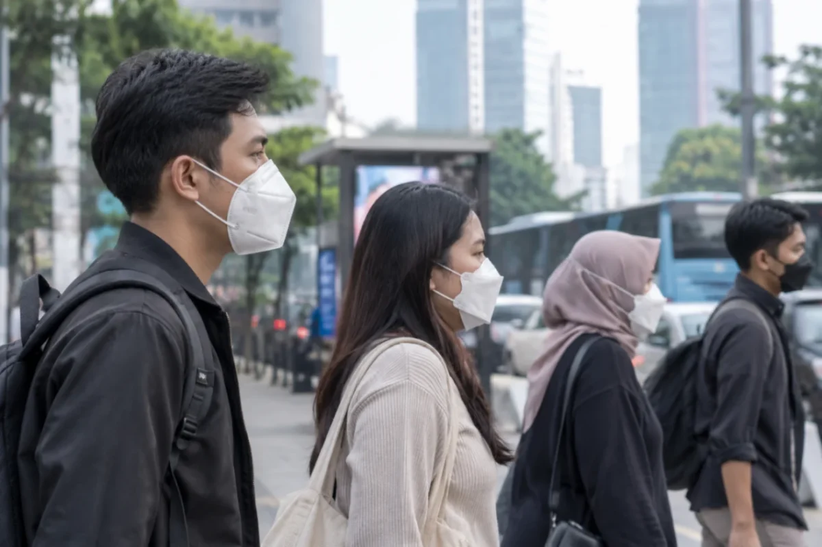 Warga mengenakan masker untuk mengurangi risiko paparan abu vulkanik Anak Krakatau yang menyebar ke sejumlah wilayah di Pulau Jawa (Ilustrasi AI : sisipublik.com)